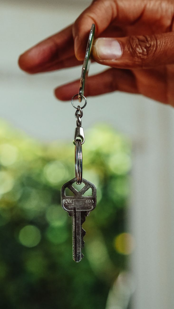 Mão segurando uma chave de imóvel pendurada num chaveiro