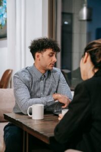 Duas pessoas conversando com atencao numa mesa baixa, com xicaras de cafe