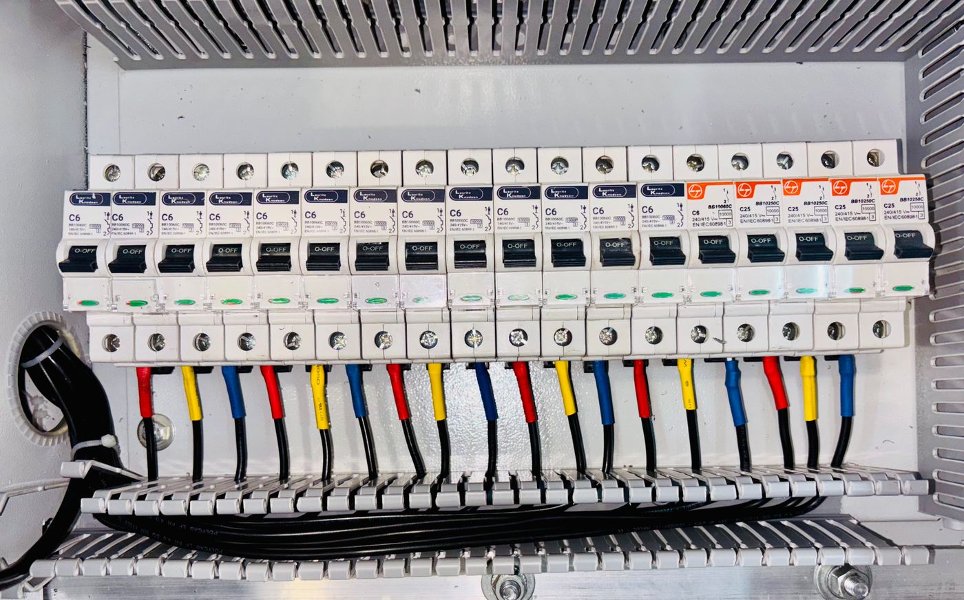 quadro de distribuição com fileira de disjuntores e fiação organizada por cores