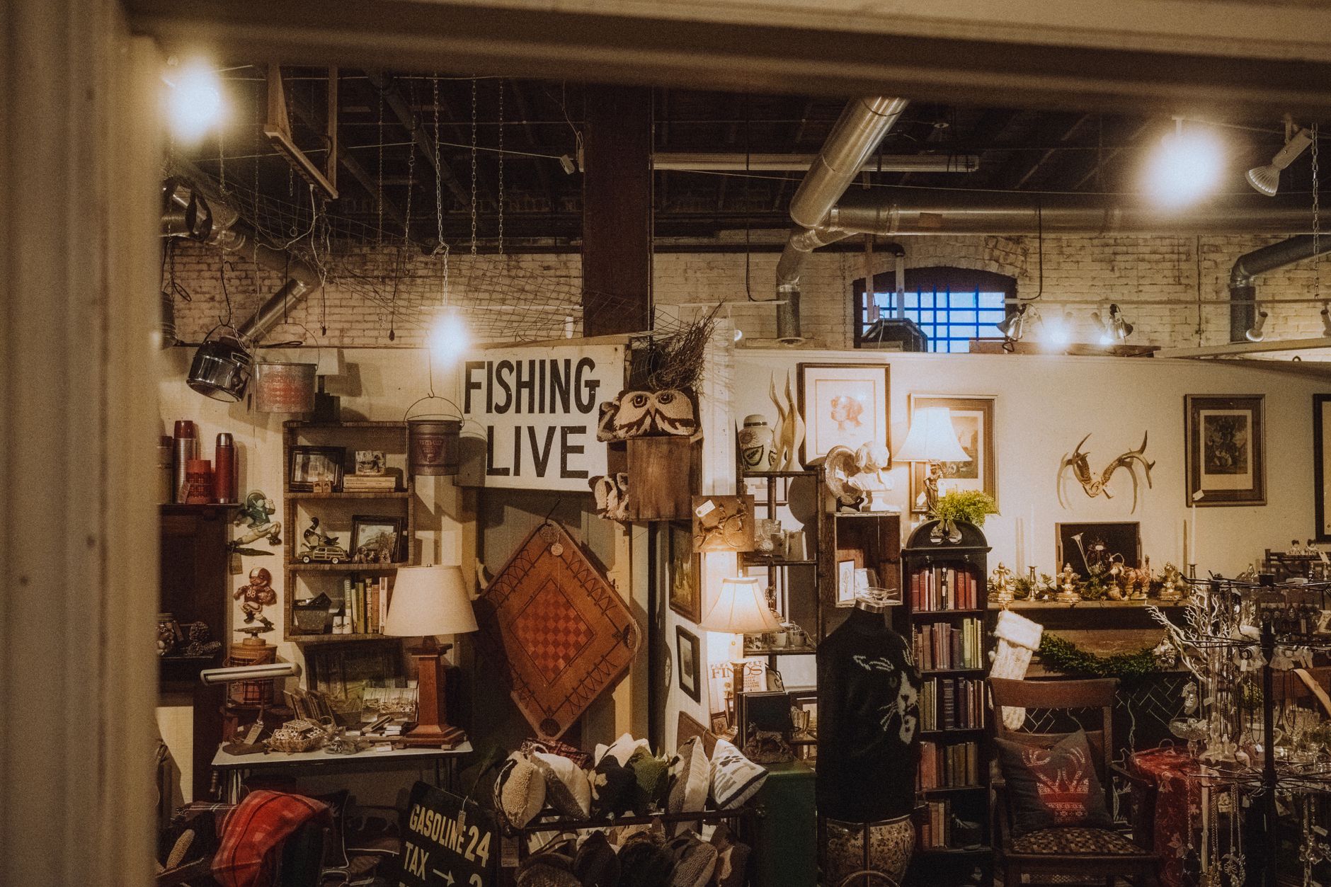 Interior de uma loja com prateleiras e paredes tomadas por objetos decorativos, quadros e luminárias
