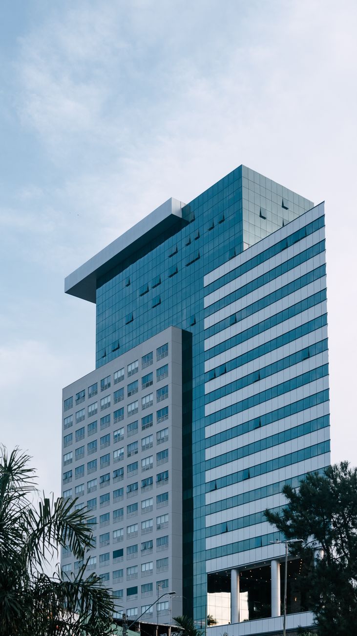 Torre corporativa de fachada de vidro, sem janelas que abram, vista de baixo para cima
