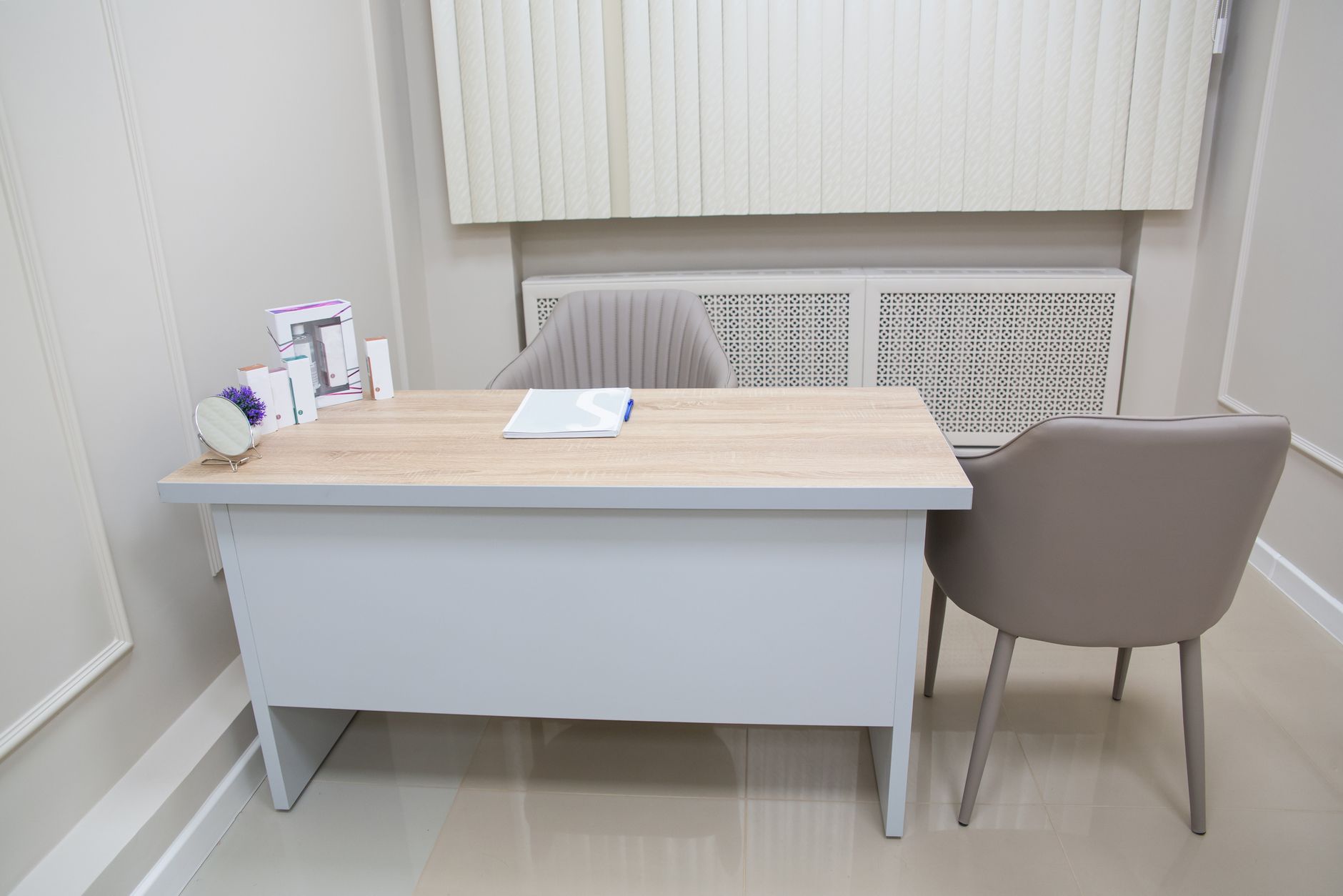 Sala de atendimento clara e simples, com mesa de madeira e duas cadeiras