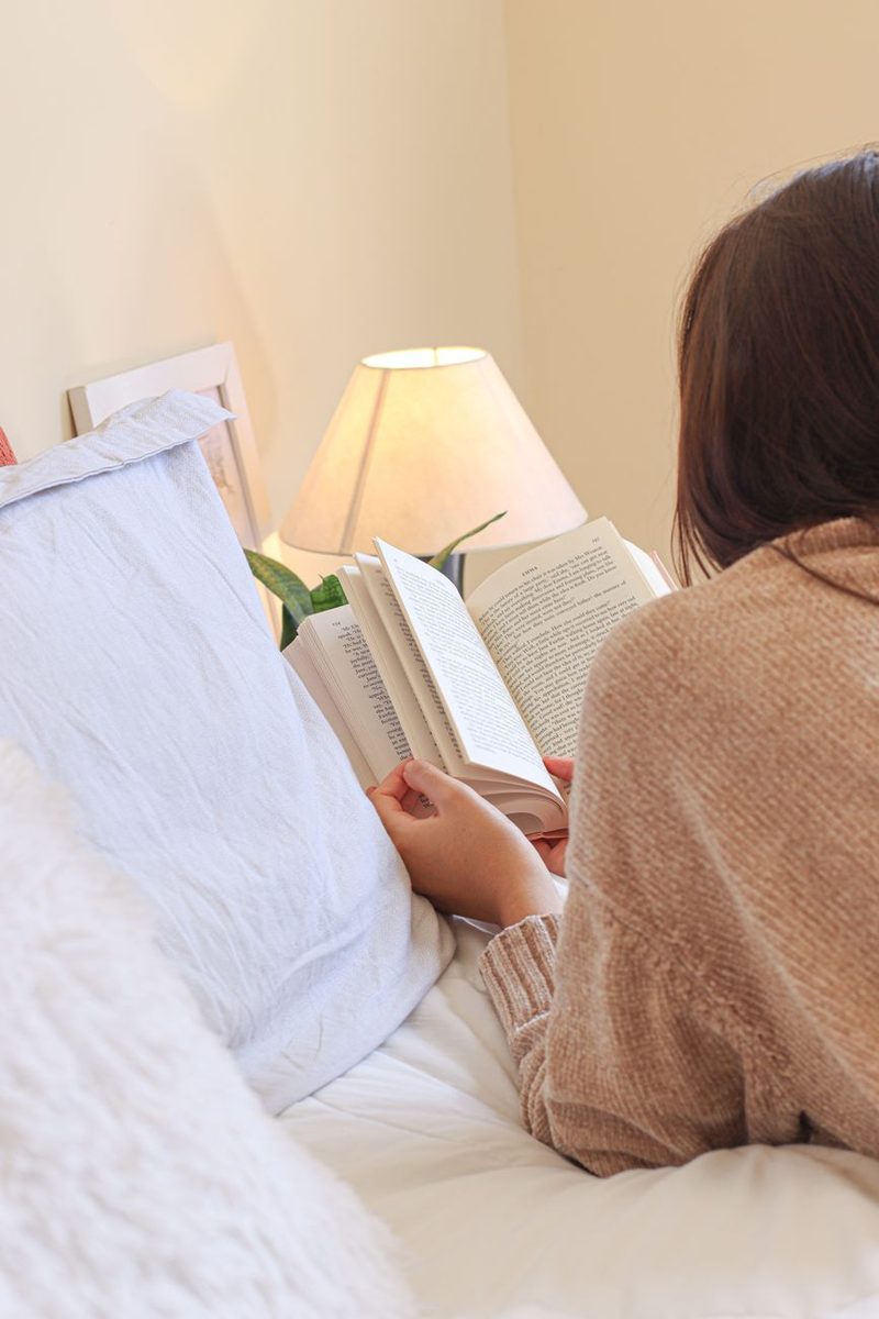 Mulher lendo na cama pela manhã, de costas