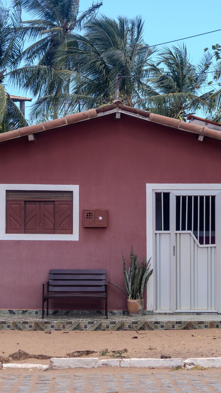 Fachada de uma casa térrea brasileira, com a janela e a porta de frente para a rua