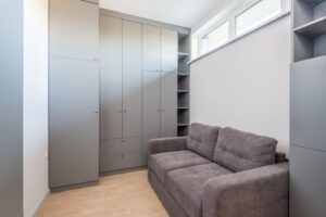 Sala compacta de apartamento pequeno com armários até o teto e um sofá de dois lugares