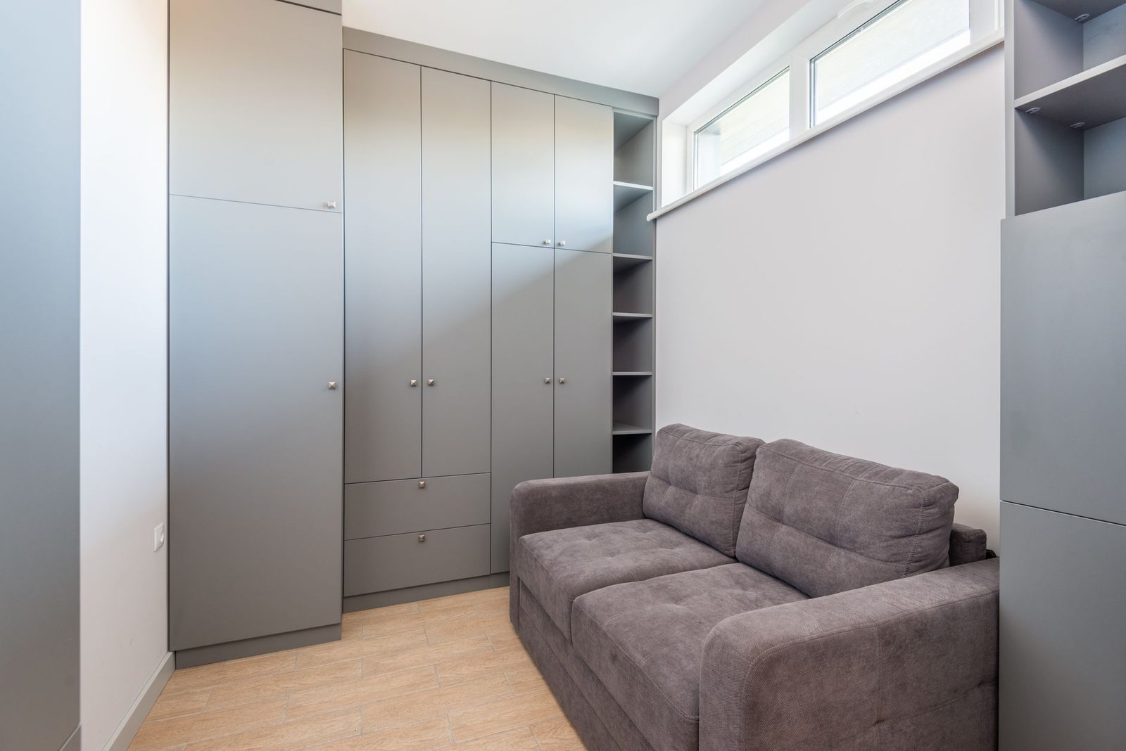 Sala compacta de apartamento pequeno com armários até o teto e um sofá de dois lugares