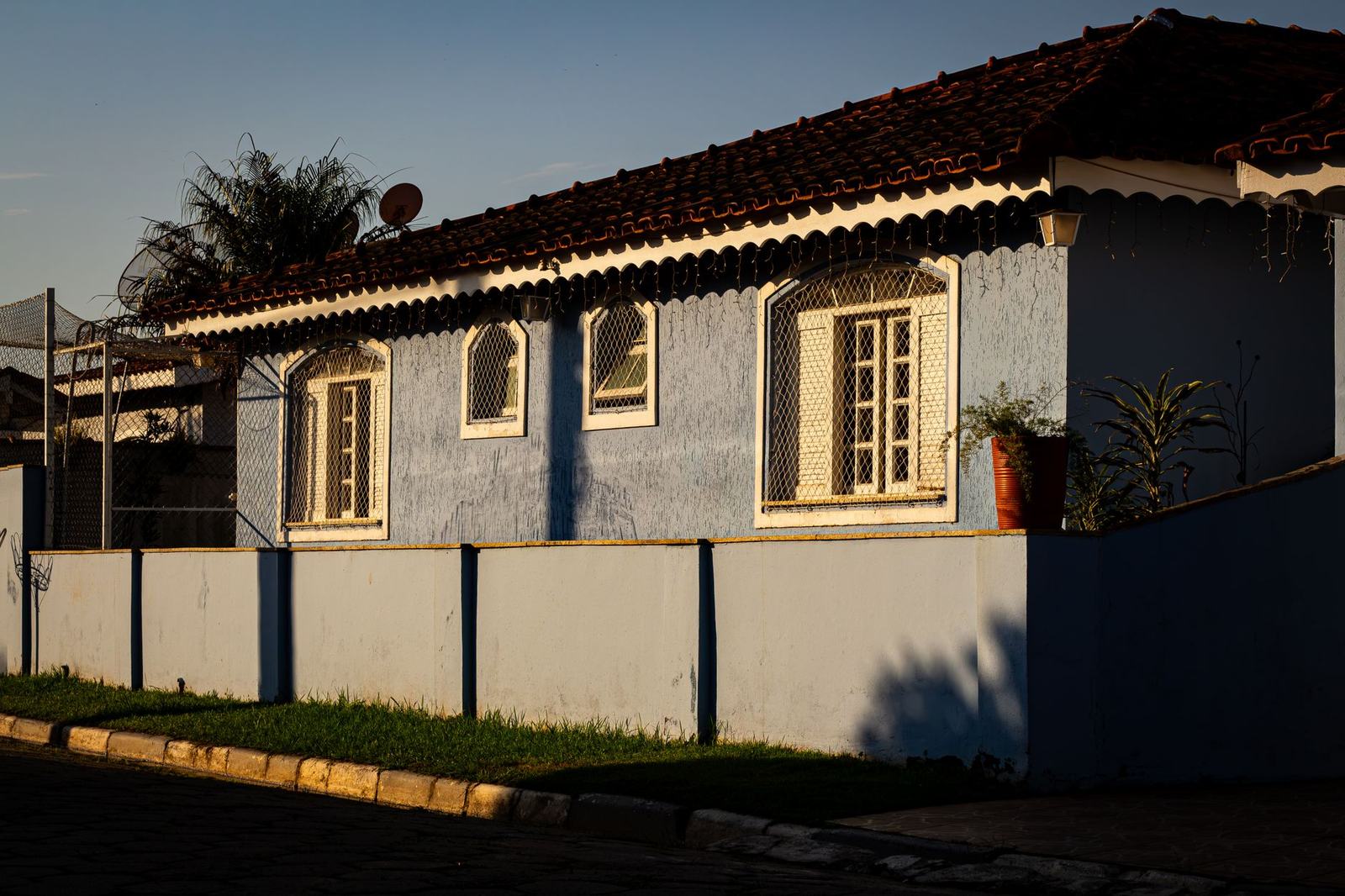 Casa brasileira de telhado de barro vista da rua, com o muro na frente