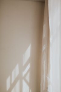 Luz da janela desenhando sombra na parede clara de um cômodo