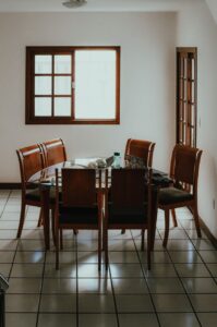 Mesa de jantar de vidro com cadeiras de madeira numa sala de casa brasileira