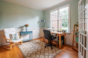 Escritório em casa com a mesa junto à janela e a cadeira de trabalho