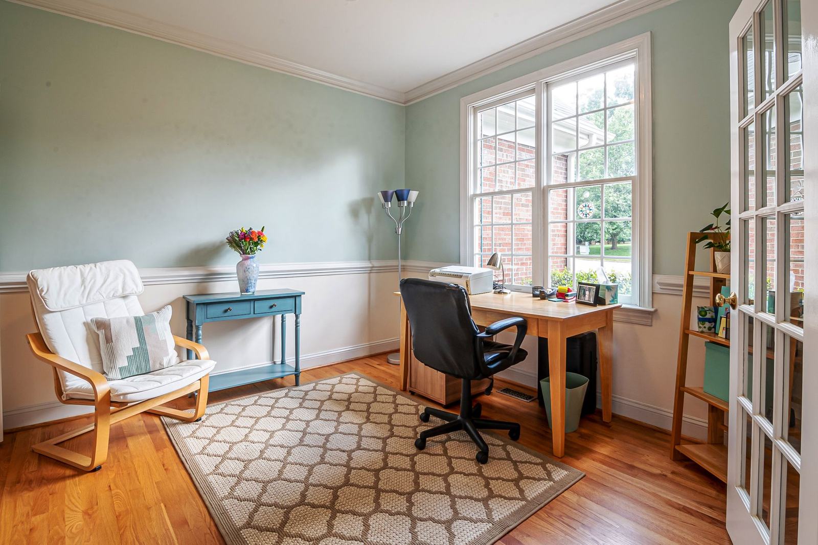 Escritório em casa com a mesa junto à janela e a cadeira de trabalho